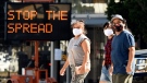 Pedestrians wear masks as they walk in front of a sign reminding the public to take steps to stop the spread of coronavirus, Thursday, July 23, 2020, in Glendale, Calif. (AP Photo/Chris Pizzello, File)