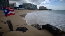 In this May 21, 2020 file photo, a Puerto Rican flag flies on an empty beach at Ocean Park, in San Juan, Puerto Rico. (AP Photo/Carlos Giusti, File) 