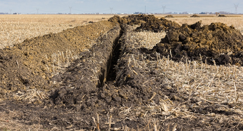 A trench is excavated in a farm field for water drainage pipe installation in this file photo.