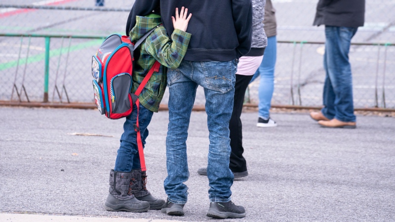 A boy hugs his father as he waits to be called to enter the schoolyard the Marie-Derome School in Saint-Jean-sur-Richelieu, Que. on Monday, May 11, 2020. Plans are being made across the country for how to safely send students back to school in the fall as the COVID-19 pandemic continues. THE CANADIAN PRESS/Paul Chiasson