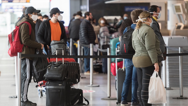 Passengers wear masks as they wait to check-in at Montreal-Pierre Elliott Trudeau International Airport, Saturday, May 16, 2020, as the COVID-19 pandemic continues in Canada and around the world. THE CANADIAN PRESS/Graham Hughes