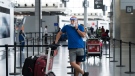 A man wearing a mask and full face shield talks on the phone at Toronto's Pearson International Airport on June 23, 2020. THE CANADIAN PRESS/Nathan Denette