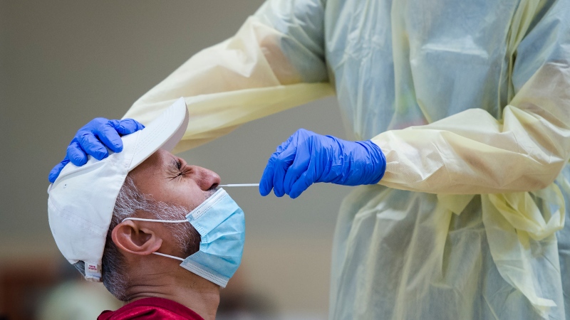 A man gets tested for COVID-19 from a health care worker at a pop-up testing centre at the Islamic Institute of Toronto during the COVID-19 pandemic in Scarborough, Ont., on Friday, May 29, 2020. (THE CANADIAN PRESS/Nathan Denette)