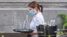 A server wears a face mask as she carries a tray of glasses and water. THE CANADIAN PRESS/Graham Hughes