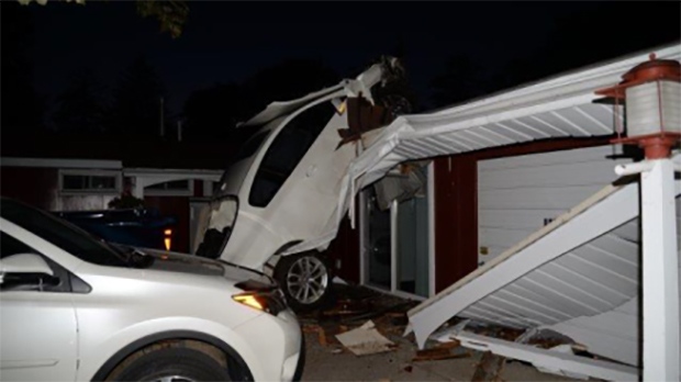A car sits wedged on a house in Sarnia, Ont. on Saturday, Aug. 29, 2020. (Source: Sarnia Police Service)