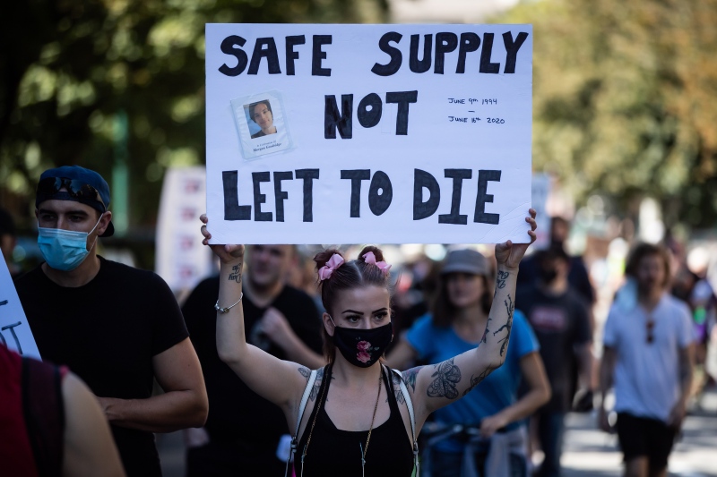 A woman holds up a sign bearing a photograph of Morgan Goodridge during a memorial march to remember victims of overdose deaths in Vancouver on Saturday, August 15, 2020. (Photos from Darryl Dyck / The Canadian Press)