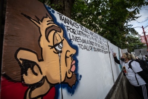 A woman writes a message on a memorial mural wall by street artist James "Smokey Devil" Hardy during a memorial to remember victims of illicit drug overdose deaths on International Overdose Awareness Day, in the Downtown Eastside of Vancouver, on Monday, August 31, 2020.  (Photos from Darryl Dyck / The Canadian Press)