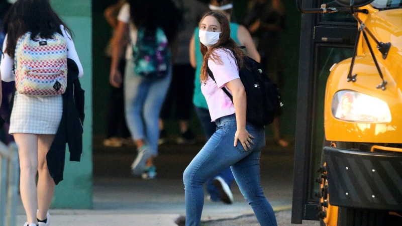 A student arrives by bus on the first day of school before the start of classes at the entrance of Gulf High School on Monday, Aug. 24, 2020, in New Port Richey, Fla. (Douglas R. Clifford/Tampa Bay Times via AP)
