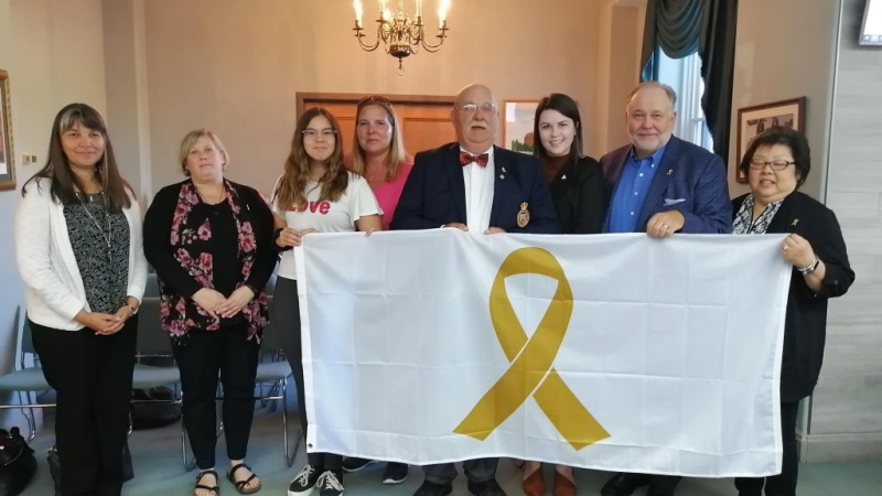 David and Maureen Jenkins (right), are seen last year with a Childcan representative, and a childhood cancer survivor, then Warden Duncan McPhail with the gold ribbon flag in honour of Childhood Cancer Awareness Month.