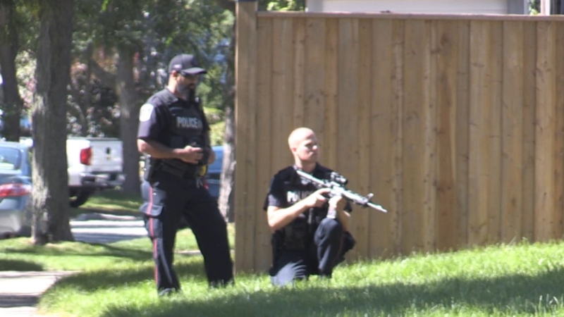 An officer with a gun can be seen on Chancton Court in London, Ont. on Saturday, Sept. 19, 2020. (Sean Irvine / CTV London)

