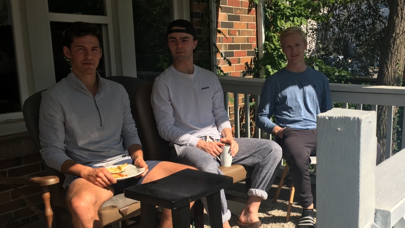 Western University student Calvin Gallina, left, and his roommates sit on their front porch on Broughdale Avenue in London, Ont. on Wednesday, Sept. 23, 2020. (Brent Lale / CTV News)