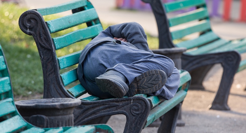 Homeless man sleeps on a bench