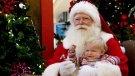 A child reacts as she sits with Santa Claus for a photo at a mall in Toronto on Friday December 10, 2010. THE CANADIAN PRESS/Chris Young
