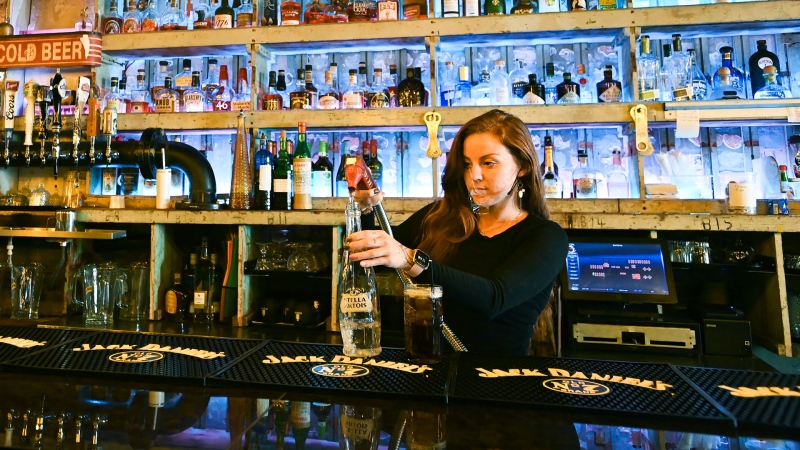 Bartender Victoria Colombe fills a drink for customers while working at Door Fifty Five bar and restaurant during the COVID-19 pandemic in the Port Credit neighbourhood of Mississauga, Ont., Friday, Oct. 9, 2020. THE CANADIAN PRESS/Nathan Denette