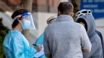 A health-care worker talks with people as they wait to be tested for COVID-19 at a testing clinic in Montreal, Sunday, October 4, 2020, as the COVID-19 pandemic continues in Canada and around the world. THE CANADIAN PRESS/Graham Hughes
