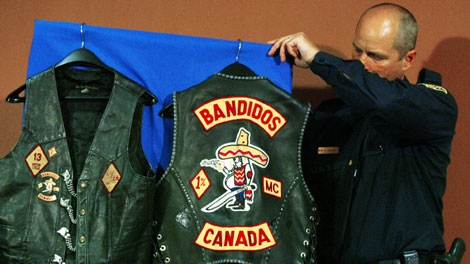 An OPP officer places biker vests seized in raids on display prior to a news conference in London, Ont., Monday April 10, 2006. (CP PHOTO/Adrian Wyld)