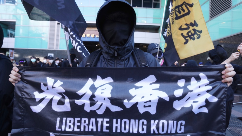 A Hong Kong protester holds a slogan "Liberate Hong Kong" during a march demand the release of the 12 Hong Kong protesters detained at sea by Chinese authorities, in Taipei, Taiwan, Sunday, Oct. 25, 2020. A group of 12 people from Hong Kong were allegedly traveling illegally by boat to Taiwan in August when Chinese authorities captured them and detained them. (AP Photo/Chiang Ying-ying)