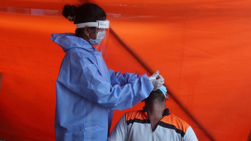 A health worker takes a nasal swab sample of a man to test for COVID-19 in Mumbai, India, Thursday, Nov. 19, 2020. (AP Photo/Rafiq Maqbool)