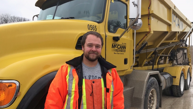 Jake Johnson of Exeter, Ont. stands by a dump truck on Monday, Nov. 30, 2020. The truck was used to save the life of a woman trapped in a burning car in Middlesex County and Johnson has been awarded a community commendation. (Sean Irvine / CTV News)