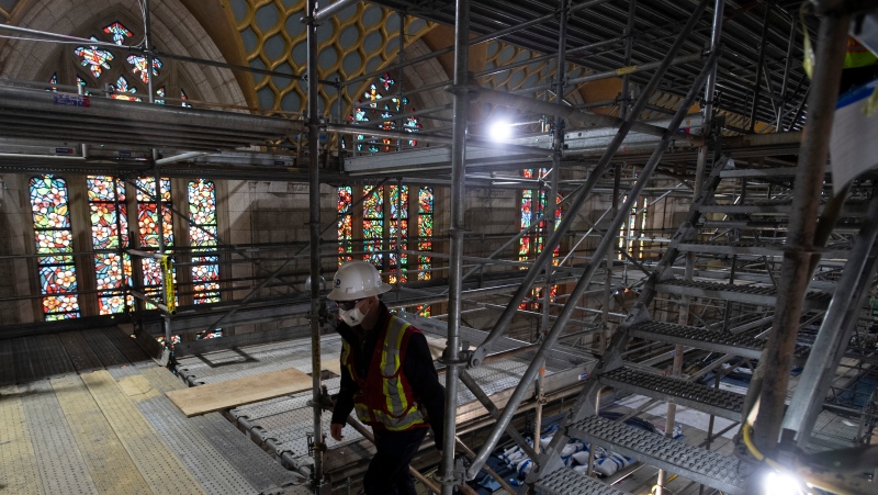 Stain glass windows are one of the few original pieces which have not been removed as a worker climbs scaffolding stairs in the Chamber of the House of Commons during a tour of the Centre block renovations Wednesday December 2, 2020 in Ottawa. THE CANADIAN PRESS/Adrian Wyld