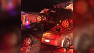 A car lands on top of two parked vehicles in a driveway on Longview Drive in Bradford, Ont., on Tues., Dec. 8, 2020. (South Simcoe Police)