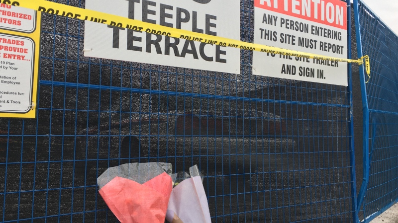 Two flower bouquets sit against a fence at 555 Teeple Terrace. Two people have died after a building at construction site collapsed. (Brent Lale/CTV News) 