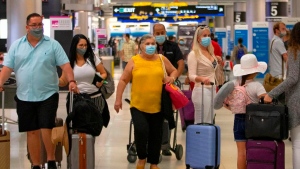 Travelers wearing protective face masks walking through Concourse D at the Miami International Airport on Sunday, Nov. 22, 2020, in Miami, Fla. THE CANADIAN PRESS/  Miami Herald / AP, David Santiago