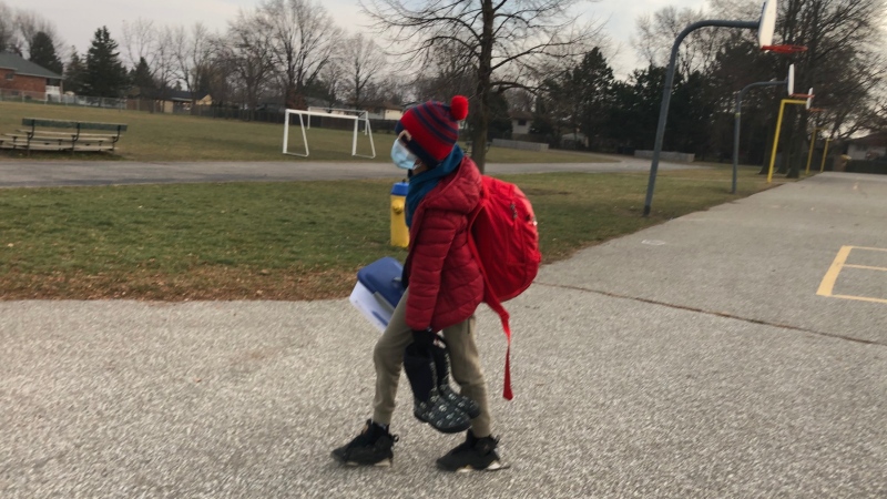 An elementary student takes home extra school supplies, boots and a stuffed backpack after schools close in Tecumseh, Ont., on Friday, Dec. 11, 2020. (CTV Windsor)