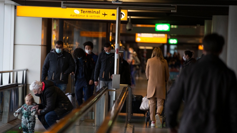 In this Friday Dec. 18, 2020, file photo, arriving and departing passengers use the flat escalators at Schiphol Airport, near Amsterdam, Netherlands. 