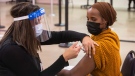 A nurse gives the first COVID-19 vaccine in Edmonton, to Sahra Kaahiye in Edmonton on Tuesday, December 15, 2020. THE CANADIAN PRESS/Jason Franson