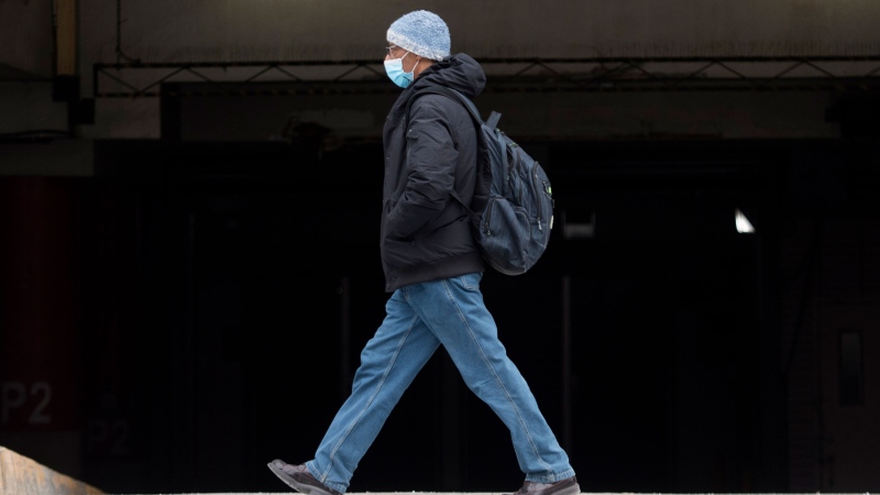 A man wears a face mask as he walks along a street in Montreal, Wednesday, December 30, 2020, as the COVID-19 pandemic continues in Canada and around the world. THE CANADIAN PRESS/Graham Hughes