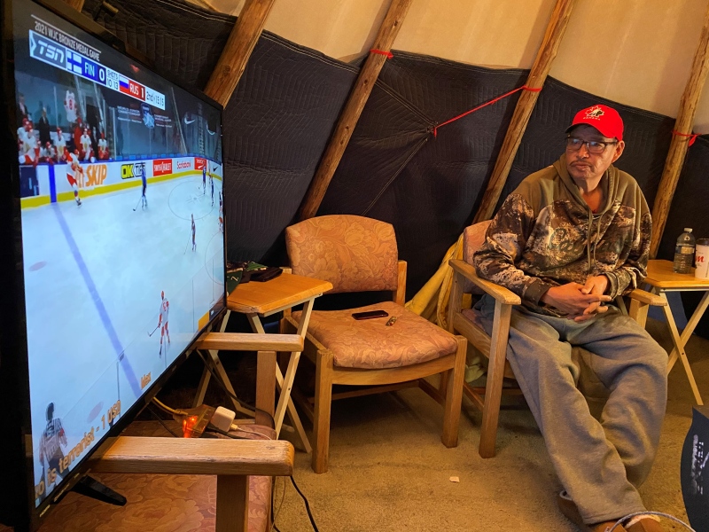 Trevlen Yuzicapi watches the world juniors bronze medal game in a tipi his sister Holly Rae Yuzicapi raised at their home on the Standing Buffalo First Nation. (Gareth Dillistone / CTV NEWS) 