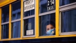A student peers through the window of a school bus as he arrives at the Bancroft Elementary School in Montreal, on August 31, 2020. THE CANADIAN PRESS/Paul Chiasson