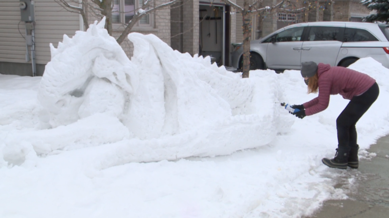 Dr. Mary Naciuk, a family doctor in south Ottawa, uses a blowtorch to touch up her sculpted snow dragon on her front lawn. Jan. 17, 2021 (Mike Mersereau / CTV News Ottawa)
