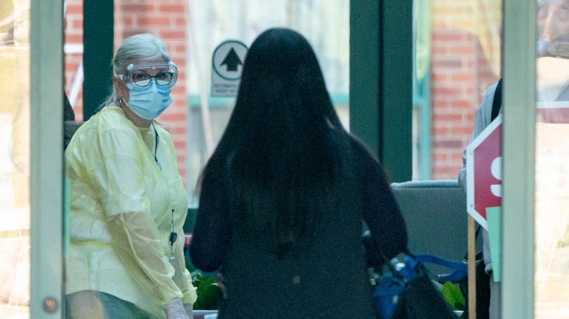 A nurse in protective gear greets a woman entering the Seven Oaks Long-Term Care Home in Toronto on Thursday, April 2, 2020.  THE CANADIAN PRESS/Frank Gunn