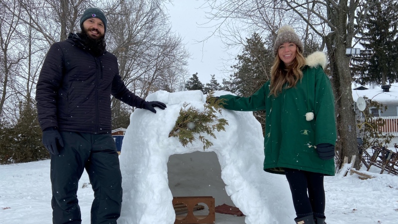 Marco Santangelo and Moca Ford pose with their igloo in Carleton Place, Ont. (Dylan Dyson / CTV News Ottawa)