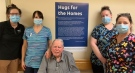 Staff and a resident at a Huron County, Ont. long-term care home stand in front an inspirational quote from Hugs for the Homes.