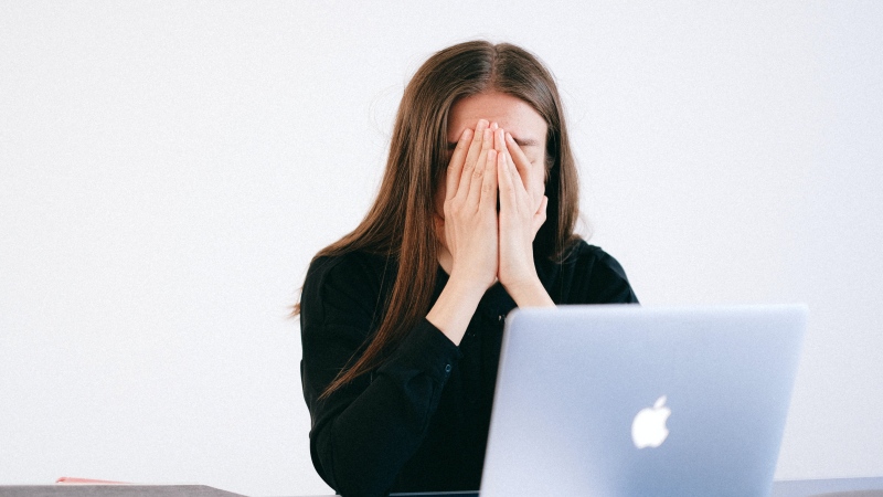 A woman is seen pressing her hands against her face in this stock photo. (Anna Shvets/Pexels)