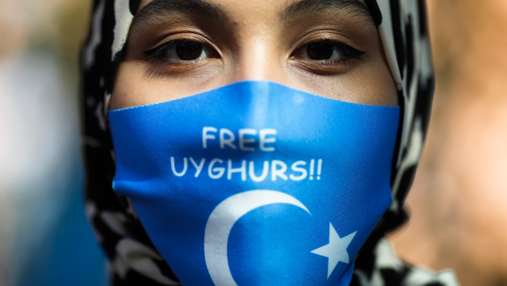 A woman wears a face mask reading 'Free Uyghurs' 