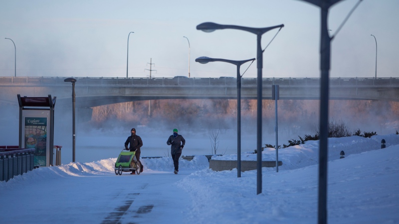 Pedestrians walk by River Landing beside the South Saskatchewan River during an extreme cold warning in Saskatoon, Sask. on Friday, February 5, 2021. THE CANADIAN PRESS/Kayle Neis