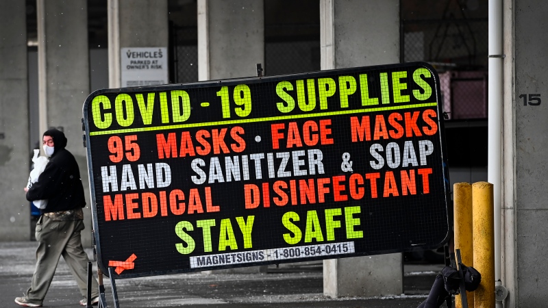 A man walks past a COVID-19 retail supplies sign during the COVID-19 pandemic in Toronto on Friday, February 5, 2021. THE CANADIAN PRESS/Nathan Denette
