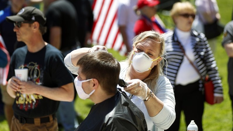 Brandi Bates gives Mike Greenbauer a free haircut at the State Capitol during a rally in Lansing, Mich., Wednesday, May 20, 2020. (AP Photo/Paul Sancya, File)