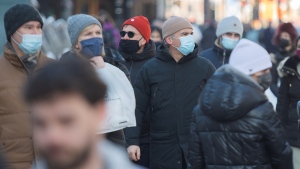 People wear face masks as they walk along a street in Montreal, Sunday, Feb. 14, 2021, as the COVID-19 pandemic continues in Canada and around the world. THE CANADIAN PRESS/Graham Hughes