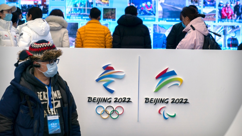 A journalist wearing a face mask to protect against the spread of the coronavirus looks at an exhibit at a visitors center at the Winter Olympic venues in Yanqing on the outskirts of Beijing, Friday, Feb. 5, 2021. (AP Photo/Mark Schiefelbein)