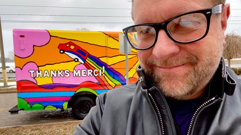Graphic artist Andrew Lewis stands in front of a Canada Post truck covered in his work in London, Ont. on Monday, March 1, 2021. (Jordyn Read / CTV News)