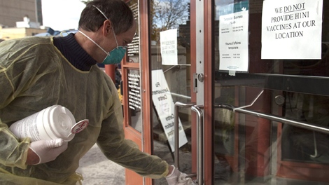 A Community Health employee cleans the door handles at the Sandy Hill Community Health centre which opened a flu assessment clinic to help reduce the pressures on emergency rooms in Ottawa on Wednesday, Nov 4, 2009.  (Pawel Dwulit / THE CANADIAN PRESS)
