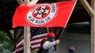 In this Sept. 1, 2018 photo, a Ku Klux Klan member waves a Klan flag during the Ku Klux Kookout where counter protests by anti-hate groups were also held at Jaycee Park in Madison, Ind. The event was organized by a chapter of the KKK, who call themselves the Honorable Sacred Knights. Madison Mayor Damon Welch is distancing his community from the group who are planning a rally in Ohio this month. Welch said Wednesday, May 15, 2019, the city doesn't "stand for any type of hate" and doesn't support the group's views. (Michelle Pemberton/The Indianapolis Star via AP)