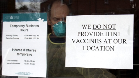 A Community Health employee is seen behind a sign at the Sandy Hill Community Health centre which opened a flu assessment clinic to help reduce the pressures on emergency rooms in Ottawa on Wednesday, Nov 4, 2009. (Pawel Dwulit  / THE CANADIAN PRESS)