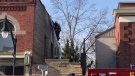 A firefighter ascends a ladder to the roof of a building where one unit was heavily damaged following a fire in West Lorne, Ont., Wednesday, March 10, 2021. (Sean Irvine / CTV News)