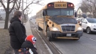 As Julian Mingo and his mother look on an SUV passes a school bus with its lights flashing on Colonel Talbot Road in London, Ont.'s Lambeth neighbourhood, Wednesday, March 17, 2021. (Sean Irvine / CTV News)